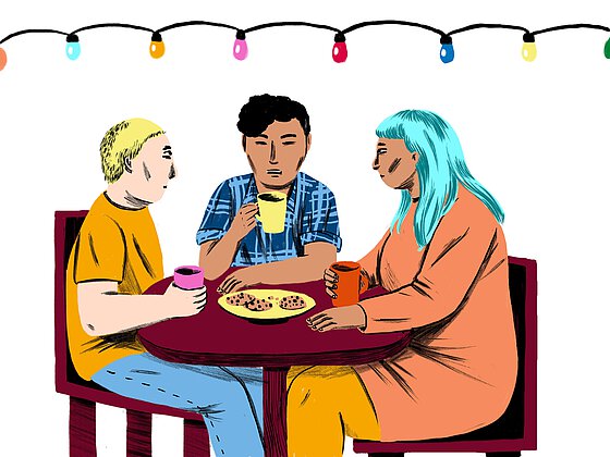 Drei Personen sitzen an einem Tisch mit Getränken und Keksen im Café und unterhalten sich.